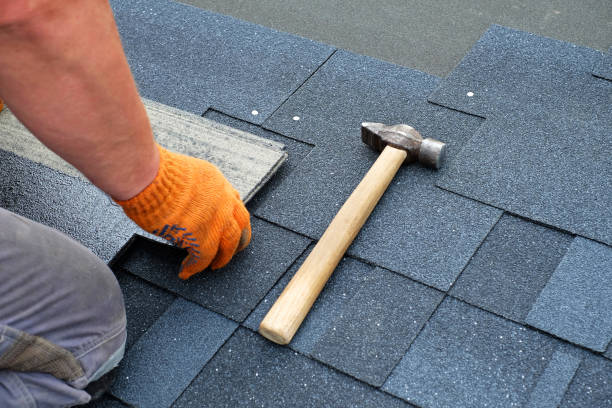 contractor hands installing bitumen roof shingles using hammer in nails. contractor hands installing bitumen roof shingles using hammer in nails.